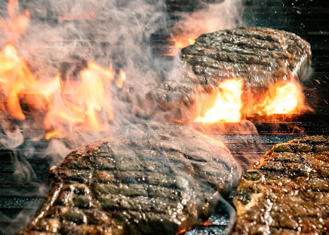 Beef burger patties grilling over flame