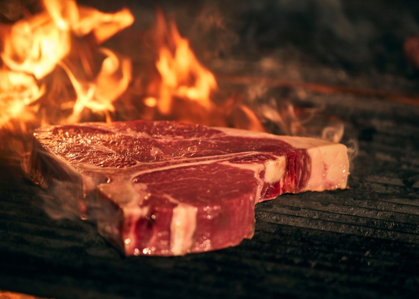 T-bone steak grilling over flame